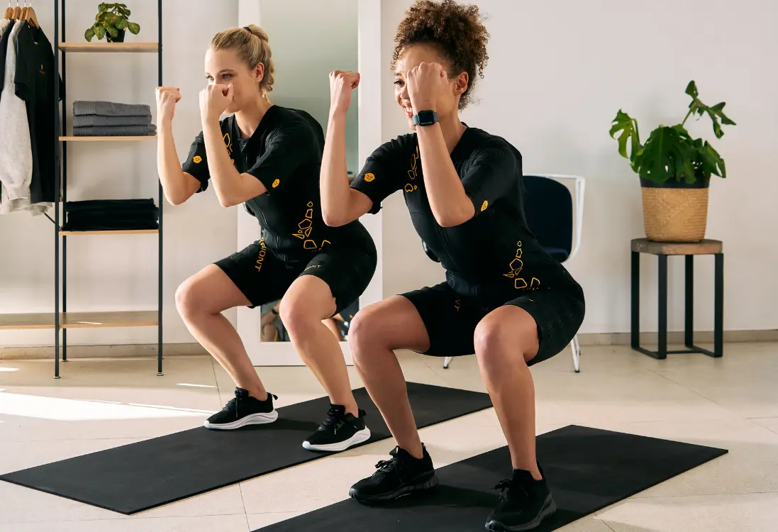 Risultati rapidi con l’allenamento EMS a Milano Due donne in tutte EMS fanno squat e usano l’allenamento EMS a Milano per ottenere risultati rapidi in poco tempo.